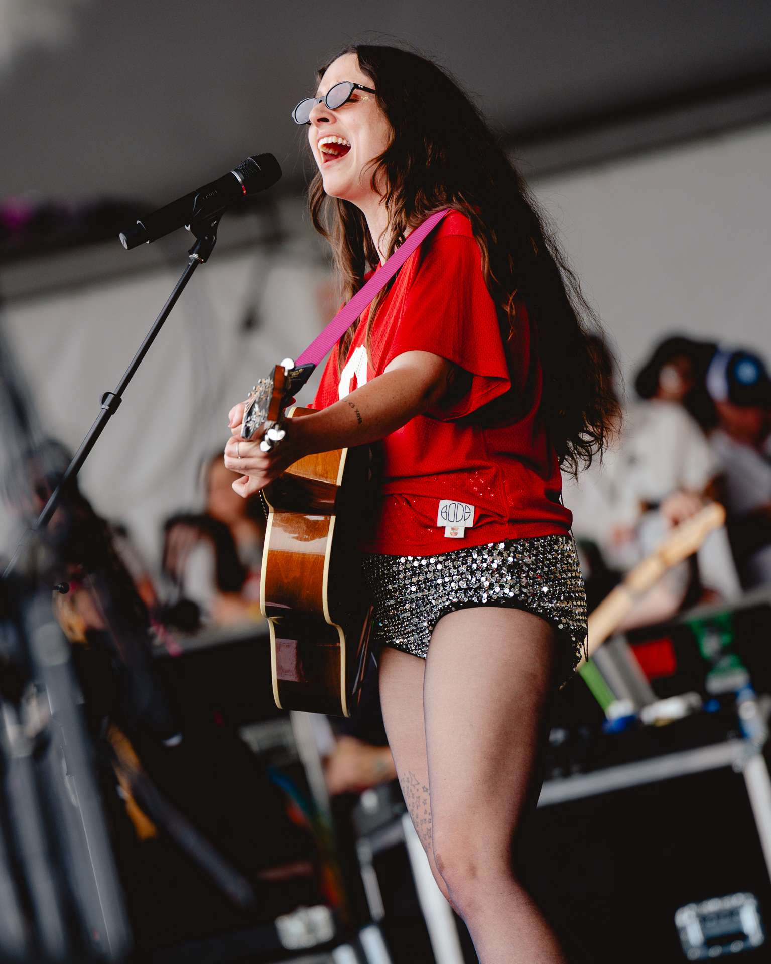 woman holding a guitar and playing it and singing in a microphone.